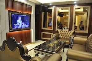 A modern living room with a flat-screen TV, leather sofas, a marble coffee table, and a large mirror.