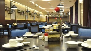 A restaurant with tables set for dining, featuring a variety of bowls, cups, and chopsticks.