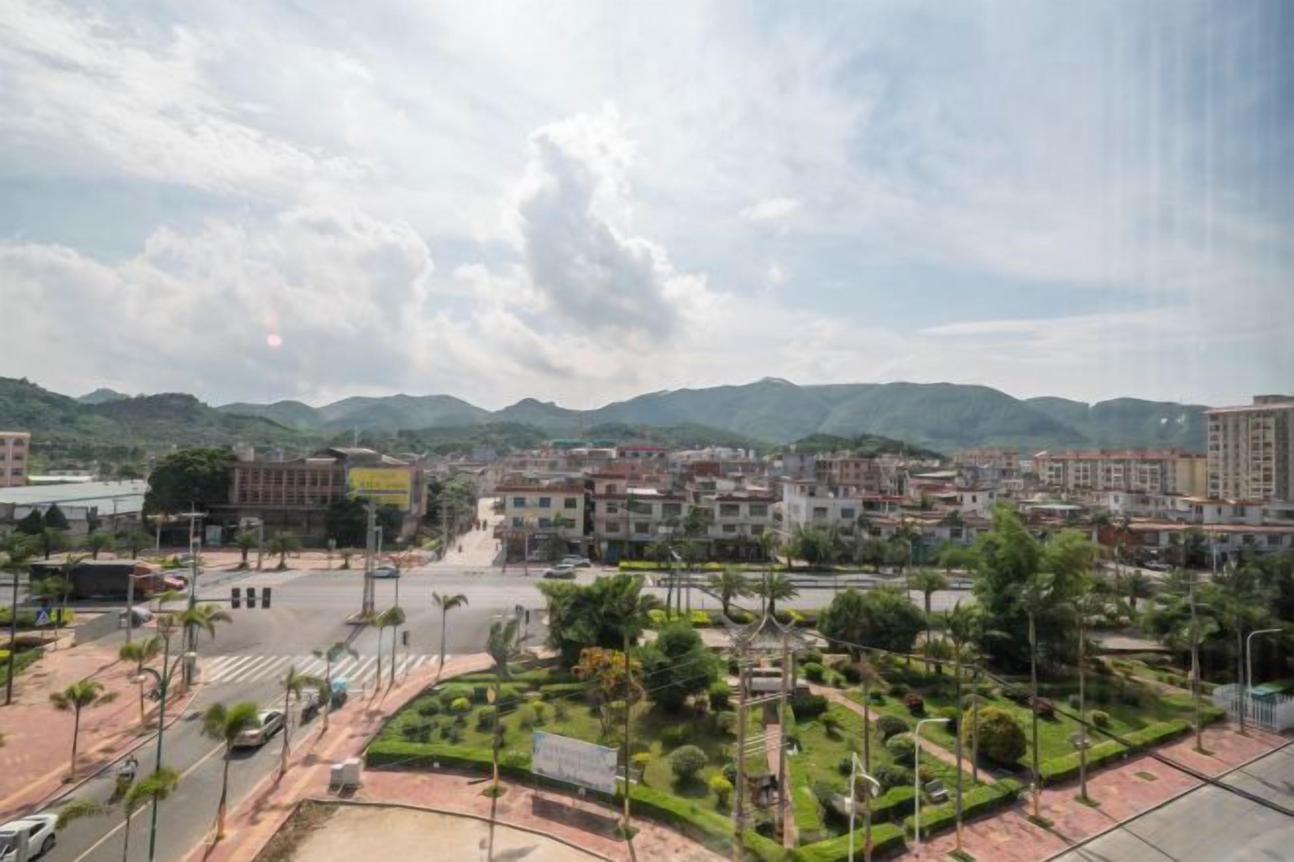 A cityscape with buildings, a plaza, and a mountainous backdrop.