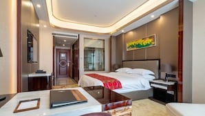 A hotel room with a bed, bedside table, lamp, and a view of the hallway.