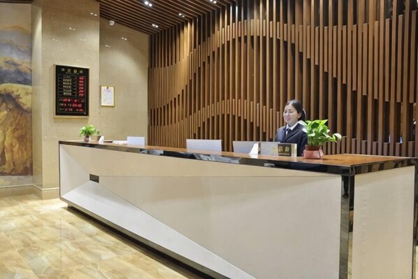 A reception desk with a modern design, a digital display board, and a wooden panel wall.