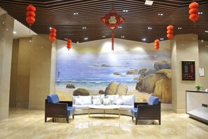 A lobby with a mural of a beach scene, a reception desk, and seating area. - Jinhengsheng Holiday Hotel (Yunxiao)