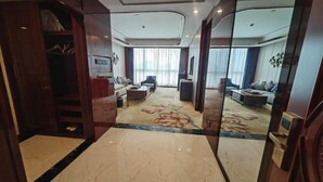 A spacious living area with a marble floor, a sofa set, a coffee table, and a large window with curtains.
