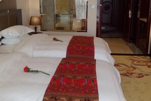 A hotel room with two beds, a red decorative runner, a single rose on the left bed, a mirror, and a door leading to another room. - Jinhengsheng Holiday Hotel (Yunxiao)