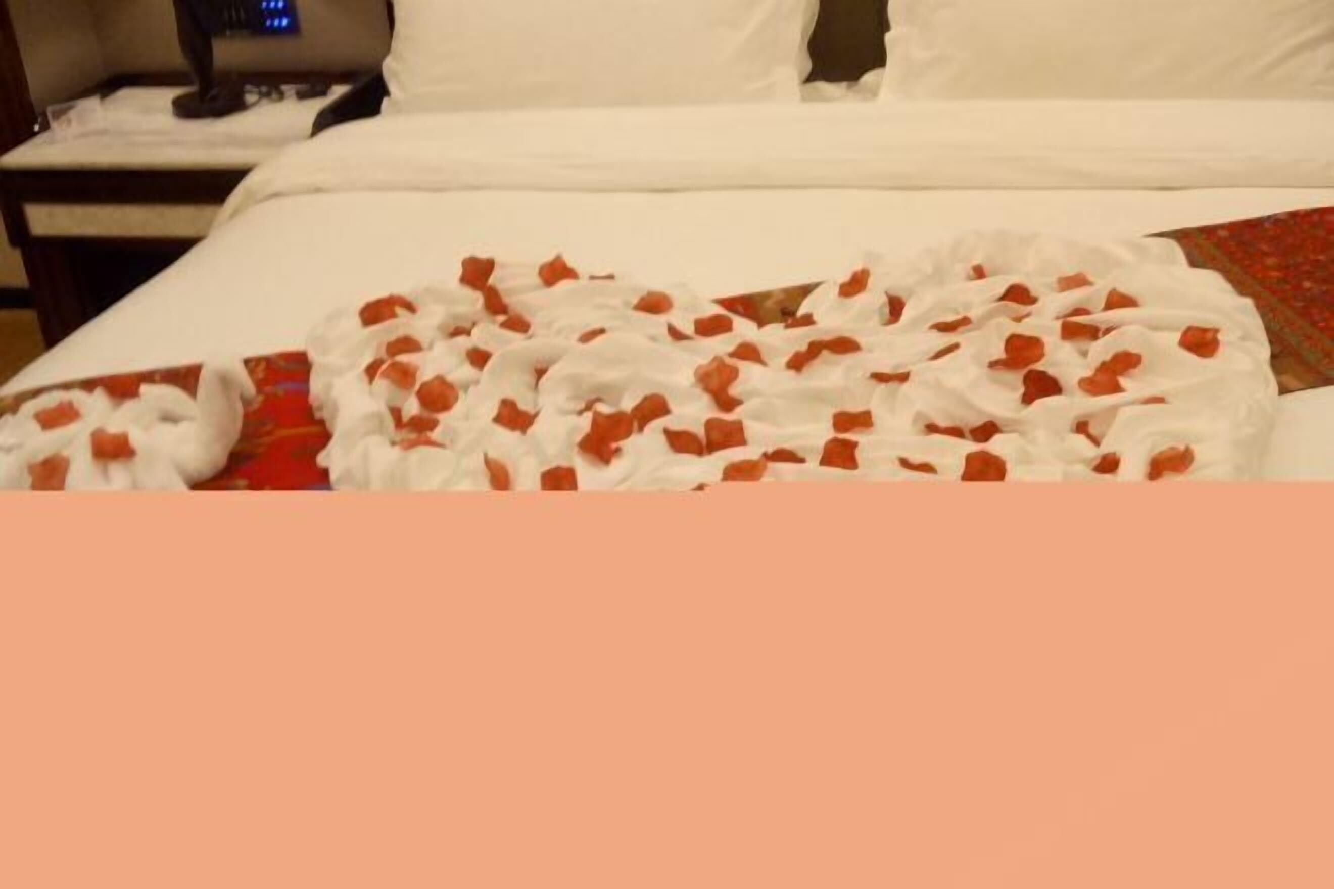 A bed with a white sheet and a red and white patterned blanket.