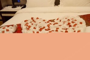 A bed with a white sheet and a red and white patterned blanket. - Jinhengsheng Holiday Hotel (Yunxiao)