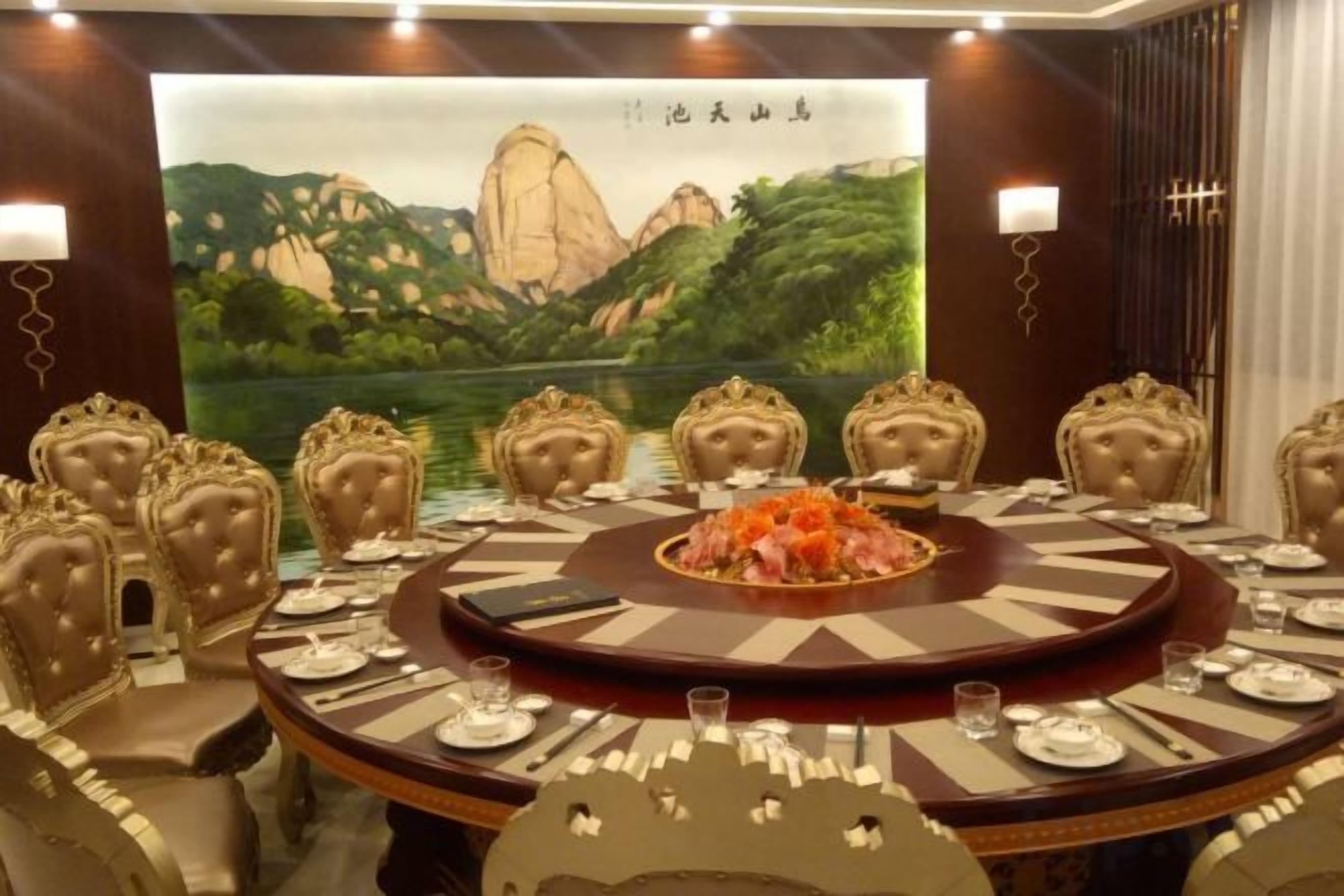 A conference room with a round table, chairs, and a large painting of a mountainous landscape.
