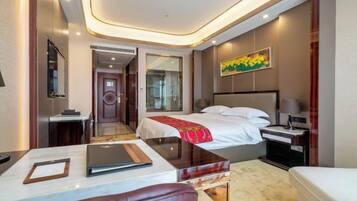 A hotel room with a bed, bedside table, lamp, and a view of the hallway.