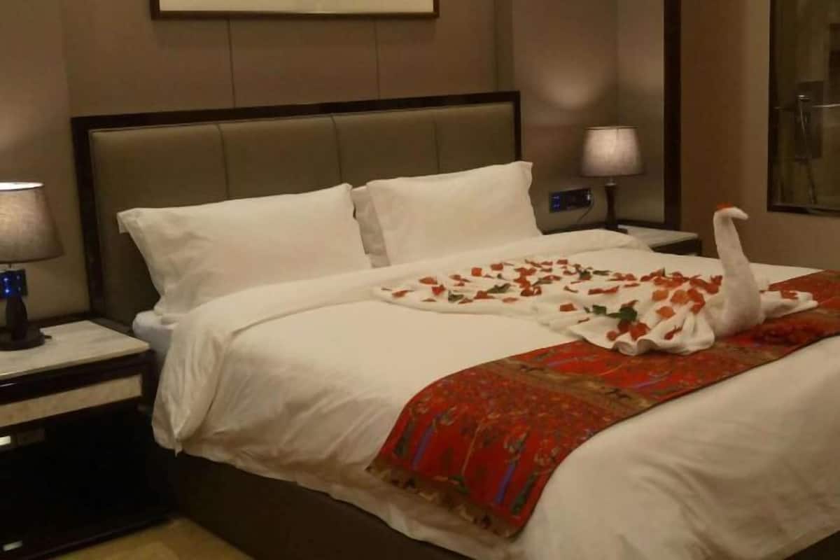 A hotel room with a bed, a nightstand, a lamp, and a swan decoration.