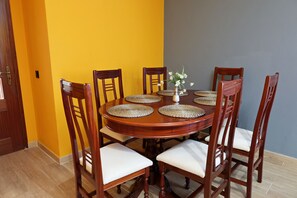 A dining table with six chairs, a vase with flowers, and a yellow and gray wall.