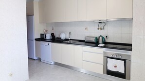 A modern kitchen with white cabinets, a dishwasher, a microwave, a toaster, and a stainless steel oven. - 2 Bedroom Apartment in Portimão (Portimão)