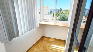 A room with a tiled floor, a window with blinds, and a view of a residential area. - 2 Bedroom Apartment in Portimão (Portimão)