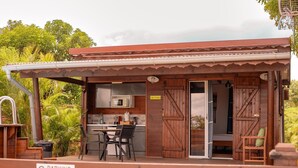 Una cabaña de madera con cocina, comedor y un patio con una silla.