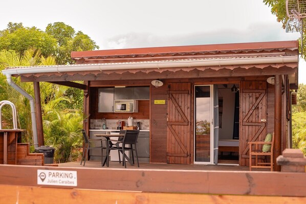 Una cabaña de madera con cocina, comedor y un patio con una silla.