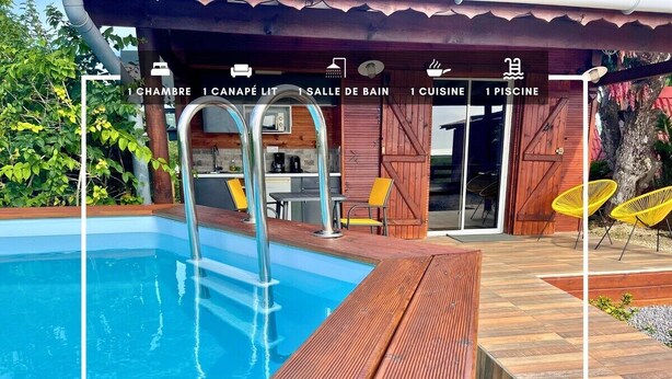 Un área de piscina con terraza de madera, zona de estar cubierta y vistas a la piscina.