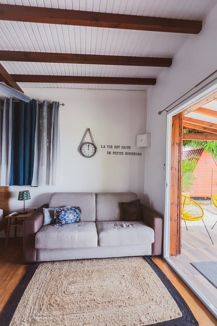 A living room with a sofa, a clock, and a French quote on the wall.