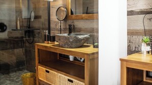 Ein Badezimmer mit Waschbecken aus Stein, einem Holzschrank, Körben aus Weidengeflecht und einem Spiegel.