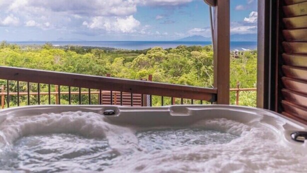 Ein Whirlpool mit Blick auf eine üppige Landschaft und einer Holzterrasse.