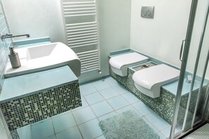 A bathroom with a sink, toilet, shower, and tiled floor.