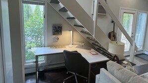 Ein modernes Arbeitszimmer mit Schreibtisch, Stuhl und einer Treppe, die zu einer oberen Ebene führt.