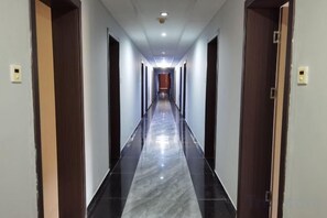 A hotel corridor with a marble floor, wooden doors, and a ceiling light fixture. - Shuangyuanhui Resort (Beijing)