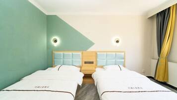 Ein Hotelzimmer mit zwei Betten, einem Holzkopfende und einer hellen Wand.