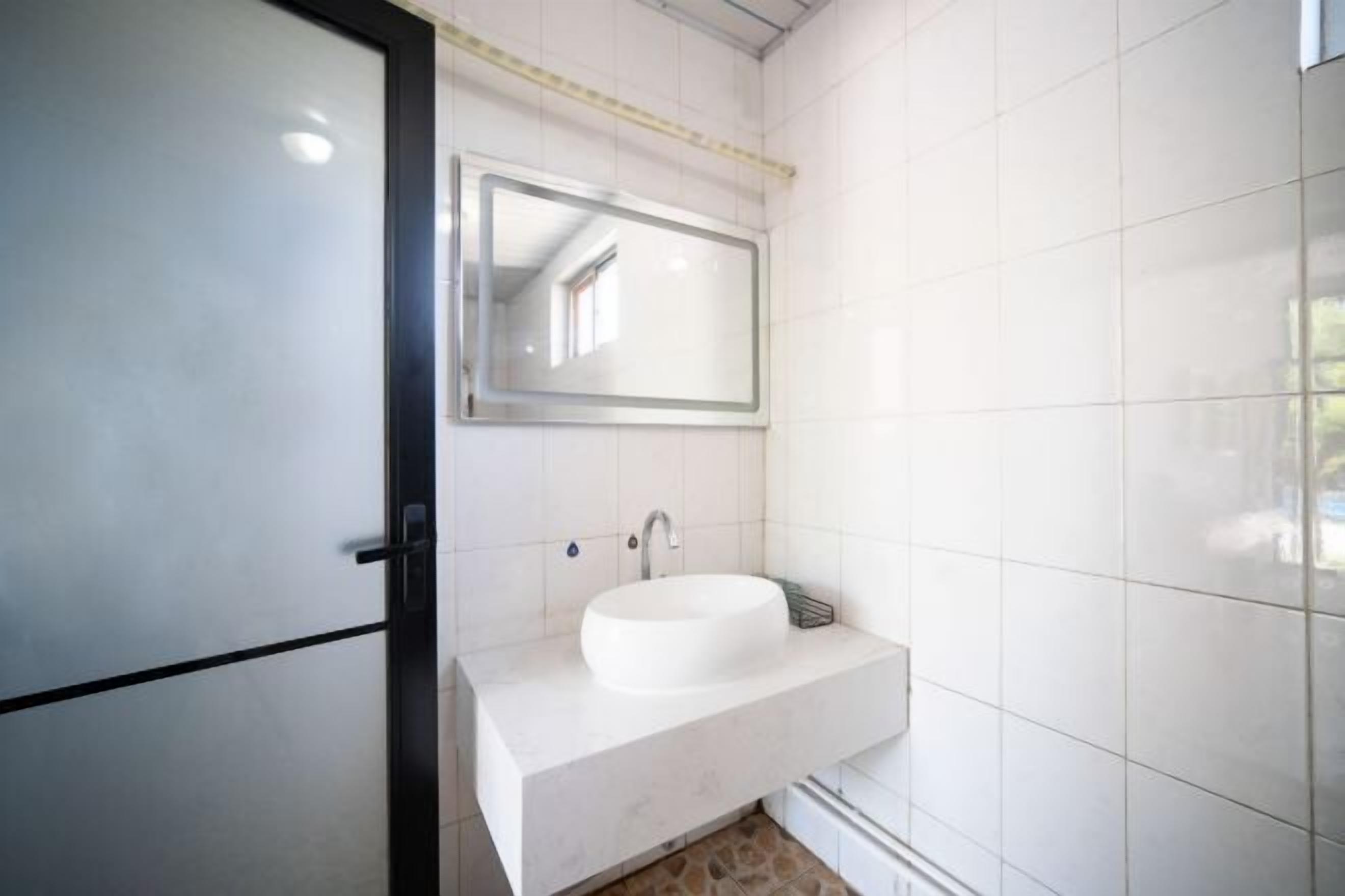 A bathroom with a white sink, a mirror, and a tiled wall.