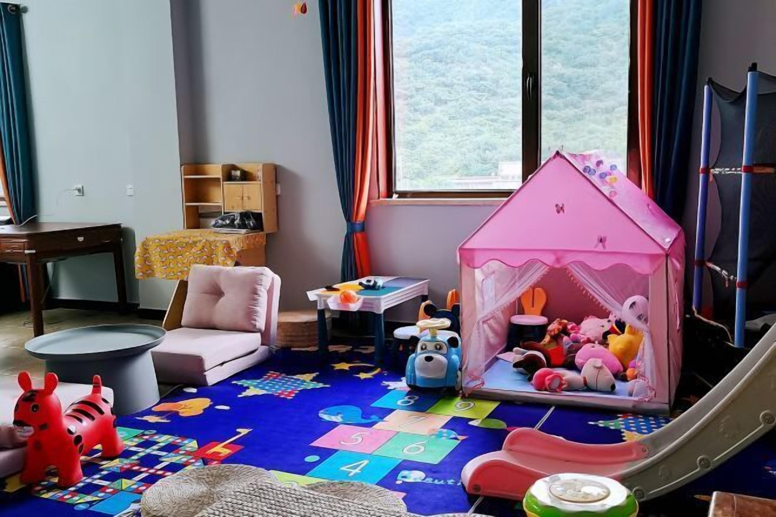 A child's playroom with a playhouse, toys, a slide, and a colorful play mat.
