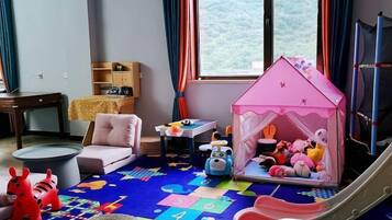 Un cuarto de juegos infantil con una casita, juguetes, un tobogán y un tapete de colores.