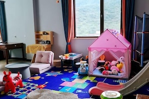 A child's playroom with a playhouse, toys, a slide, and a colorful play mat. - Shuangyuanhui Resort (Beijing)