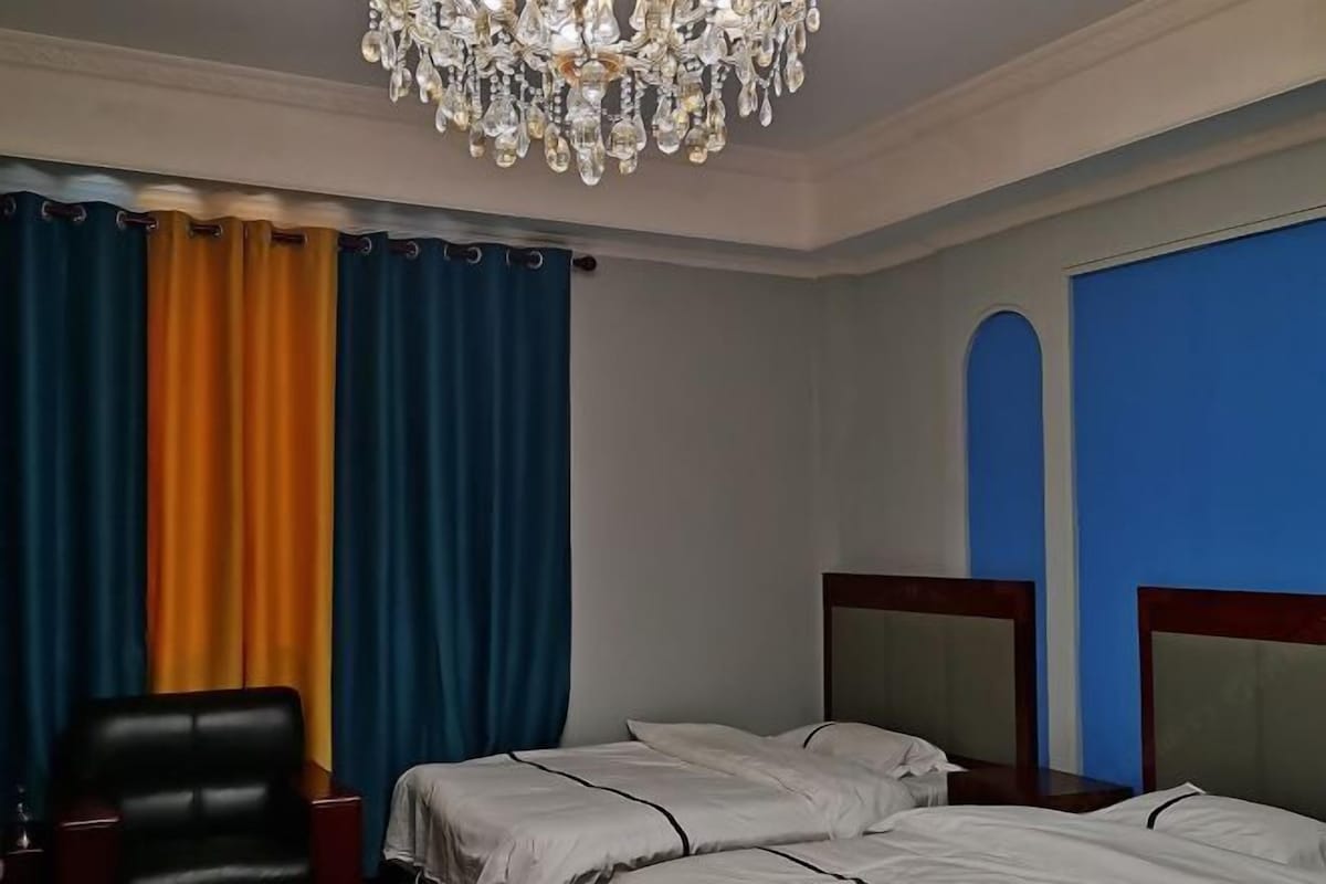 A hotel room with two beds, a chandelier, and curtains.