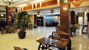 A lobby with a large potted plant, wooden tables and chairs, and a chandelier. - Shuangyuanhui Resort (Beijing)