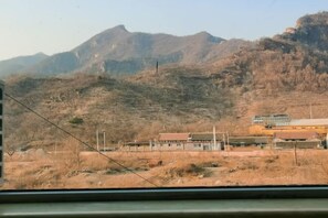 A view from a vehicle window of a mountainous area with a building that appears to be a hotel or motel, featuring a flat roof and a simple, utilitarian design. - Shuangyuanhui Resort (Beijing)
