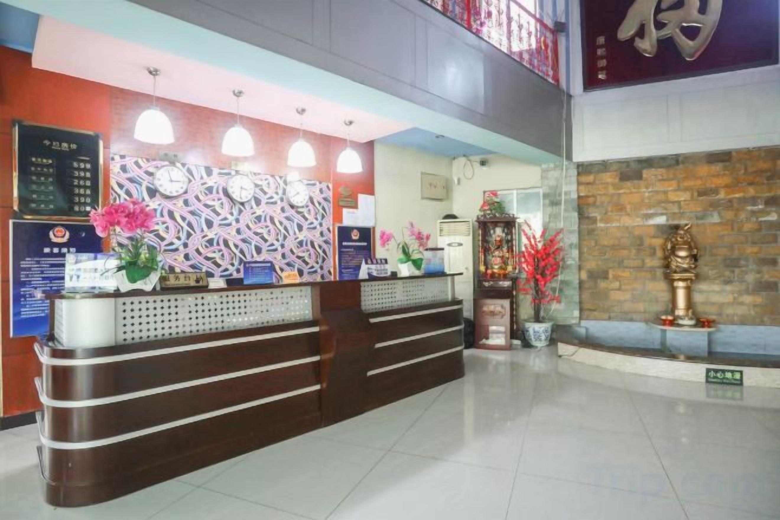 Ein Hotel-Empfangsbereich mit Empfangstresen, Wanduhr und einer Zimmerpflanze.