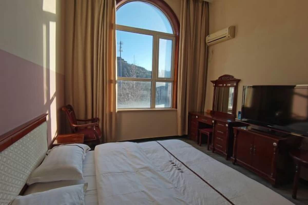 Ein Hotelzimmer mit einem großen Bett, einem Fernseher, einem Schreibtisch und einem Stuhl.