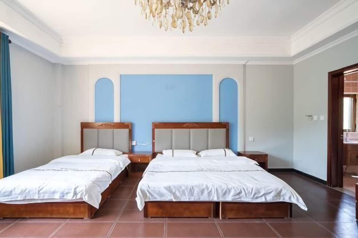Ein Zimmer mit zwei Betten, einer Chandelüster und einer blauen Wand.