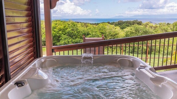 A hot tub with a view of a lush landscape and the ocean.