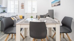 Un'area pranzo moderna con un tavolo rettangolare, quattro sedie e un televisore a parete.