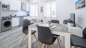 Una cucina moderna con mobili bianchi, una lavatrice e un'area pranzo con tavolo e sedie.