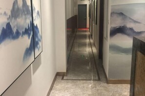 Un pasillo con obras de arte en las paredes, un suelo reflectante y una puerta al final.