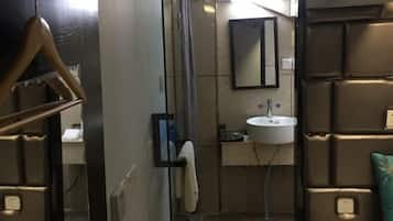 A bathroom with a mirror, sink, towel rack, and a shower area.