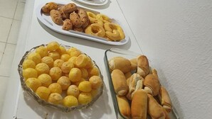 Ein Buffet mit verschiedenen Speisen, darunter Gebäck, Brot und ein mit Schokolade überzogener Donut.