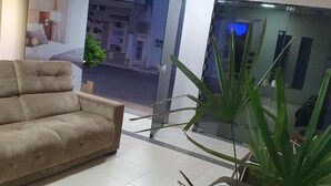 Eine Hotellobby mit einem beigefarbenen Sofa, einem kleinen Tisch und einer Zimmerpflanze.