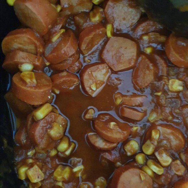 A close-up of a dish with sliced sausages and corn in a sauce. - Entre Rios Hotel (Paraiso Do Tocantins)