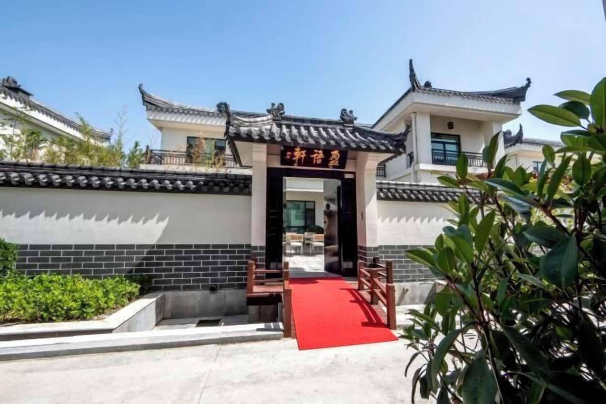 A traditional Chinese building entrance with a red carpet leading to the door.