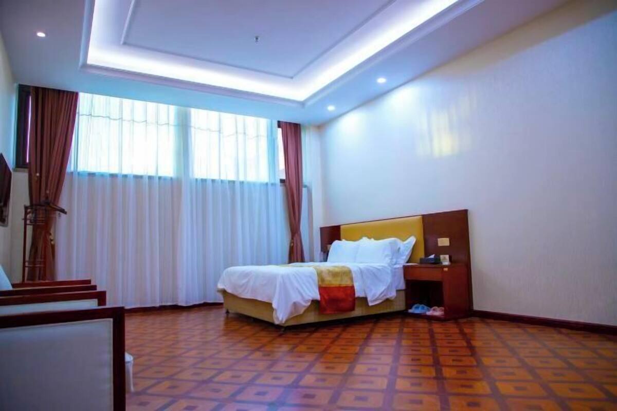 A hotel room with a bed, a desk, a chair, and a window with curtains.