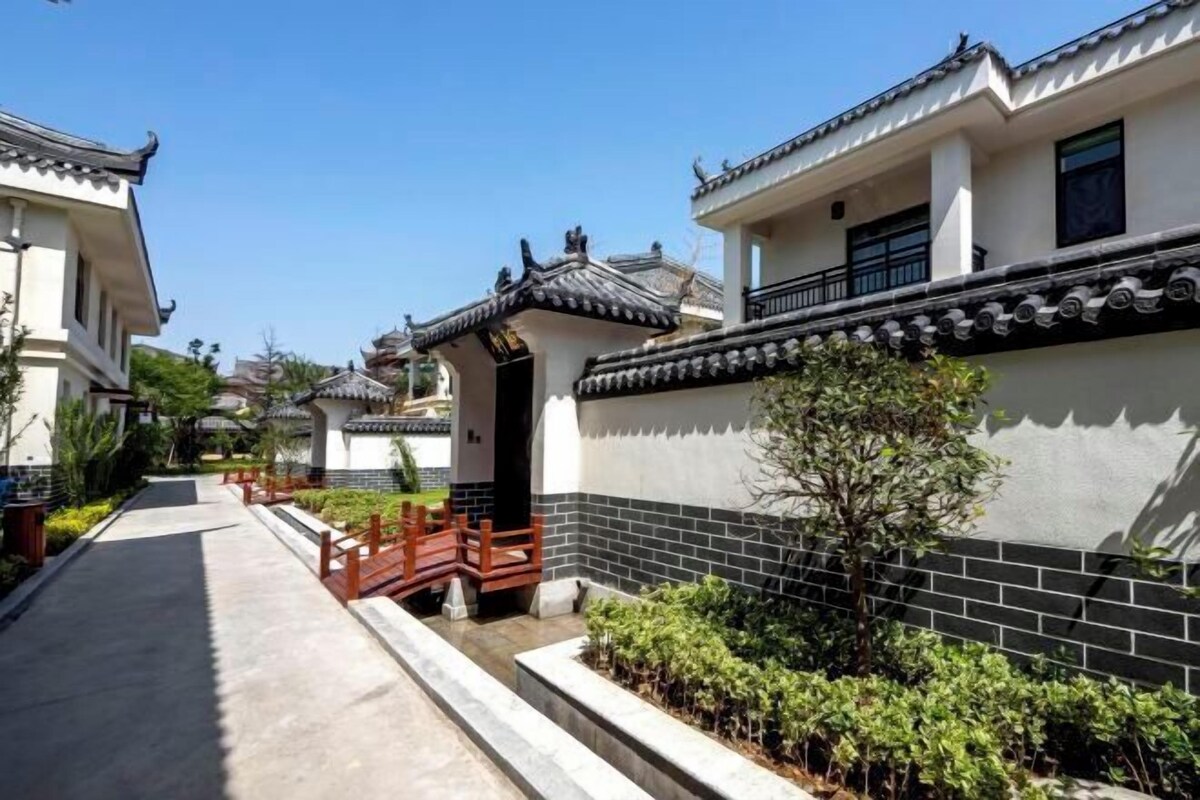 A traditional-style building with a tiled roof, a wooden fence, and a pathway leading to the entrance.
