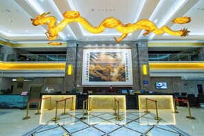 A hotel lobby with a reception desk, a large dragon decoration, and a prominent poster on the wall. - Kunlong Hot Spring Hotel (Yantai)