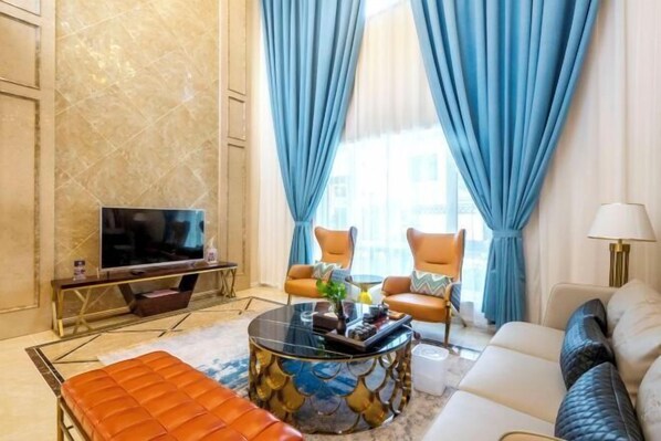 A modern living room with a sofa, armchairs, a coffee table, and a television. - Kunlong Hot Spring Hotel (Yantai)