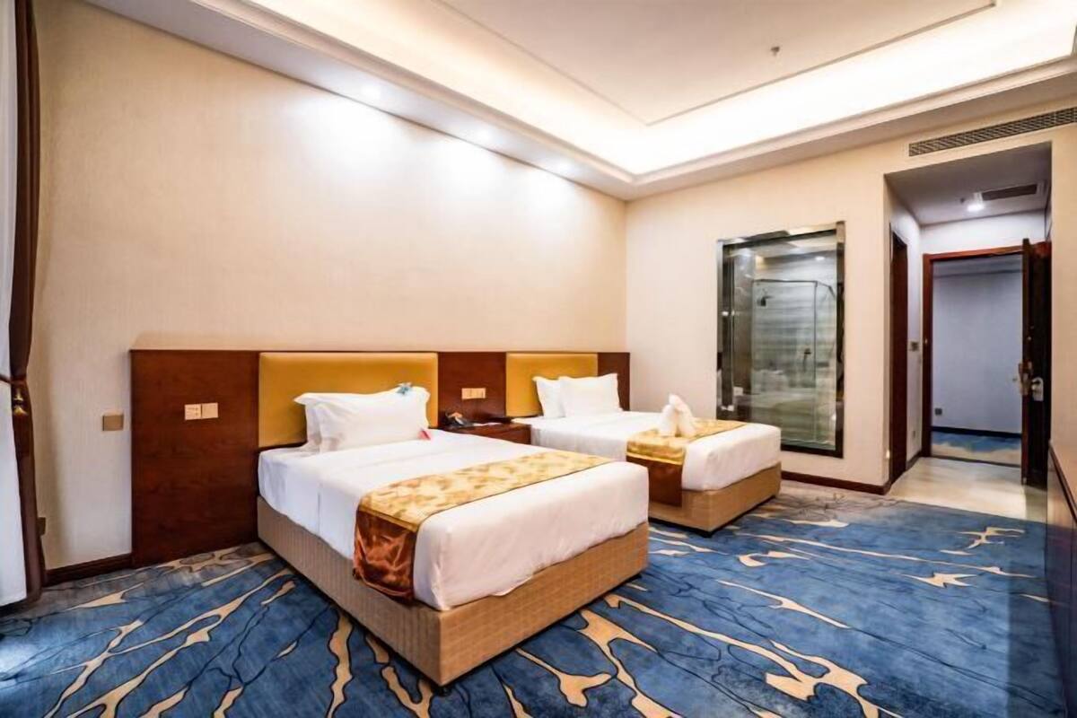 A hotel room with two beds, a large mirror, and a blue patterned carpet.